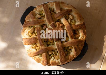 Table top food photography of baked open yeast dough Rhubarb and Apple Pie in a round black ceramic backing form standing on wooden table in a bright Stock Photo