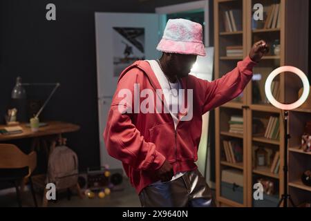 Waist up portrait of Black young man dancing hip-hop style indoors and wearing pink outfit Stock Photo