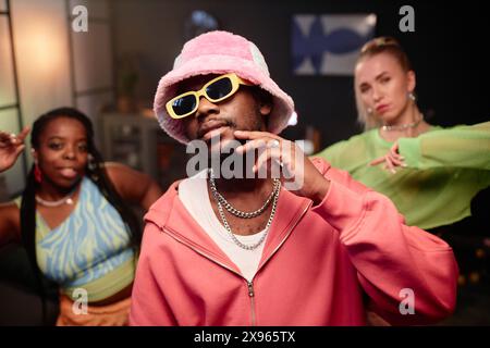 Waist up portrait of contemporary dance crew indoors with focus on Black man wearing pink outfit looking at camera with style Stock Photo