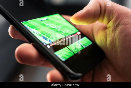 Watching sport stream with phone. Football or soccer live on tv. Game and match video in smartphone. Online broadcast mobile app for fans. Stock Photo