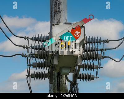 Electricity distribution 3 phase high voltage circuit breaker isolator switch in OFF position used to disconnect power supply on overhead cables. UK Stock Photo