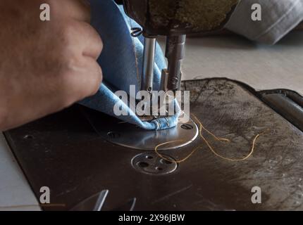 Woman hands sewn fabric repairs on sewing machine in Sewing Process. Stock Photo