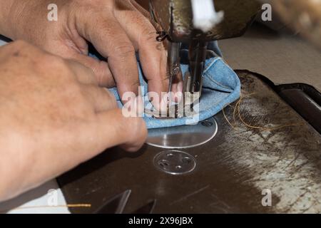 Woman hands sewn fabric repairs on sewing machine in Sewing Process. Stock Photo
