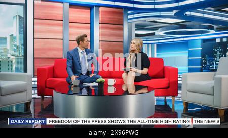 Talk Show TV Program and News Discussion: Two Cheerful Presenters Talk, Have Fun. Cable Channel Hosts Have Friendly Conversation. Mock-up Television Studio and Newsroom Entertainment Concept Stock Photo