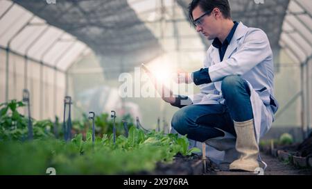 Portrait of handsome agricultural researcher holding tablet while working on research at plantation in industrial greenhouse Stock Photo