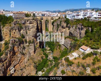 Gorge with old bridge and white houses on the rocks, mountains in the background, sunny day, aerial view, waterfall, Ronda, Malaga, Andalusia, Spain Stock Photo