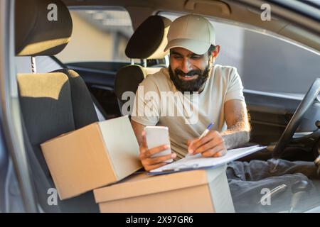 A Delivery Driver With Beard and Cap Checks Delivery Information Stock Photo