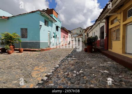 339 Stone-paved Calle Llano Street, curving slope-up from the riverside area between one-storey colonial houses on both sides. Sancti Spiritus-Cuba. Stock Photo