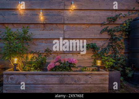 Small solar lantern in planter and on the fence. Solar lamp in garden Stock Photo