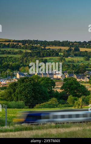 Building constructing houses in scenic rural valley (loss of green field land, loco speeding past) - Burley-in-Wharfedale, West Yorkshire England UK Stock Photo