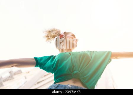 young cheerful woman dancing in the city and wearing headphones Stock Photo