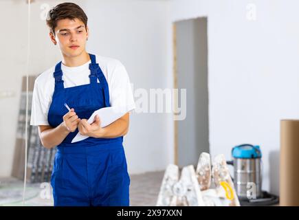 Young builder making checklist while planning indoor building overhaul Stock Photo