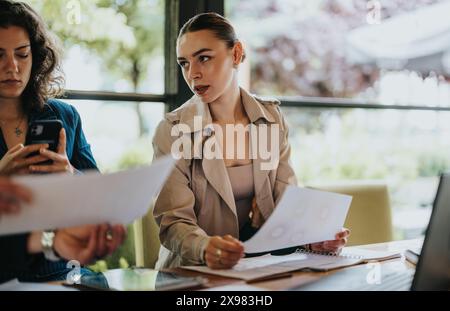 Young business partners working on project at a cafe, analyzing reports, creating growth strategies Stock Photo