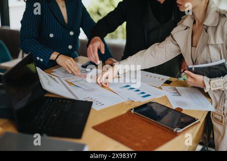 Business team collaborating on project, analyzing data and charts on table Stock Photo