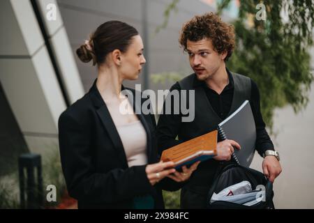 Two business professionals having an outdoor discussion while exchanging notebooks Stock Photo