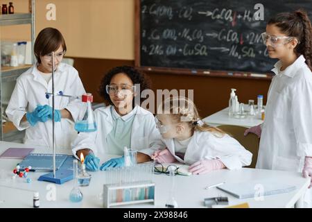 High angle view of ethnically diverse boys and girls wearing lab coats and goggles doing experiment in Chemistry class Stock Photo