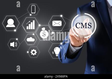 CMS. Man using virtual screen, closeup. Scheme with icons on dark background Stock Photo