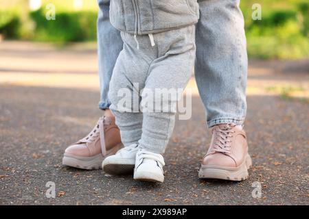 Mother teaching her baby how to walk outdoors, closeup Stock Photo