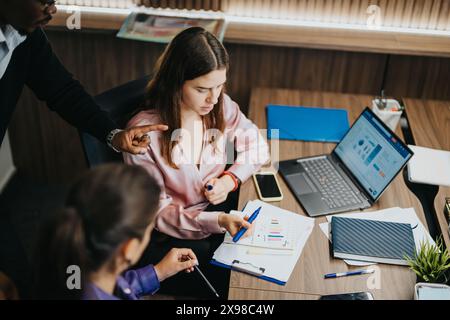 Diverse team of professionals engaged in a business meeting in an office setting, analyzing data and strategizing growth. Stock Photo