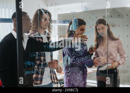 Diverse business team brainstorming with sticky notes on glass wall in modern office Stock Photo