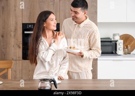 Happy young couple having breakfast in kitchen Stock Photo
