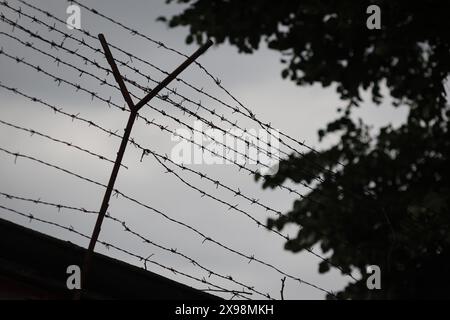 Shallow depth of field (selective focus) details with barbed wire on the outer wall of a prison in Eastern Europe Stock Photo