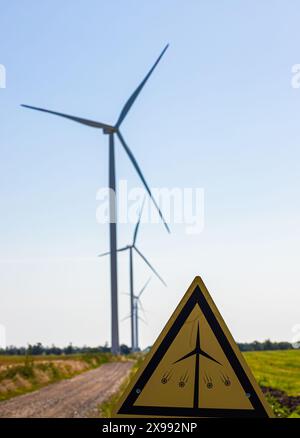 Wind Turbines with a caution sign warning of the dangers of approaching the turbine. Stock Photo