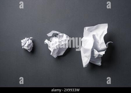 Very, medium and slightly crumpled paper balls on dark gray background Stock Photo