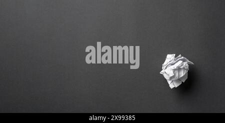 White paper crumpled into a ball on a dark gray background Stock Photo