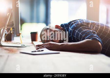 Business man, sleeping and tired by computer for fatigue, overworked or deadline in office. Programmer or developer with depression, burnout or Stock Photo
