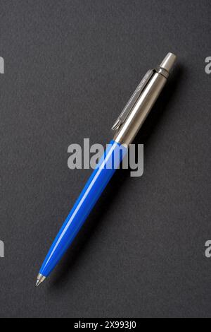 Blue plastic and metal ballpoint pen on dark gray isolated background Stock Photo