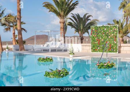 Cutely decorated swimming pool area prepared for a Hindu wedding or festive event with floating flower bouquets of lush green leaves and flowers Stock Photo