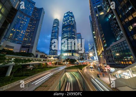 Skyscraper buildings and traffic on road with blurred cars light trails at night, Hong Kong, China Stock Photo