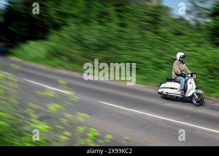 1960's Lambretta scooter travelling along an English country road Stock Photo