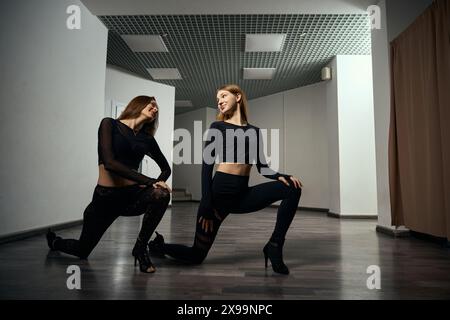 Stiletto dancers doing leg stretching exercise before dance session Stock Photo