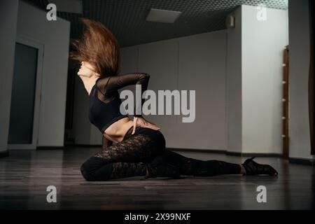 Young woman in stilettos practicing floorwork moves in dance studio Stock Photo