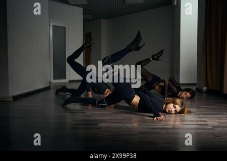 Trio of stiletto dancers practicing floorwork moves in studio Stock Photo