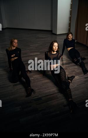 Three women in stilettos performing floorwork dance in studio Stock Photo