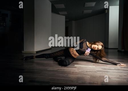 Choreographer in high heels and black attire practicing floorwork moves Stock Photo