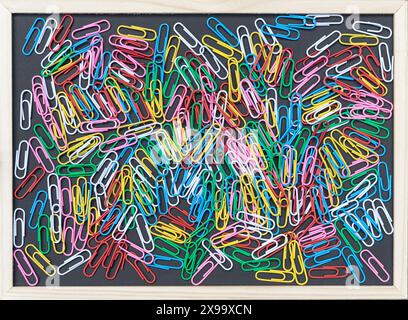 Background with a black board with colorful paper clips and copy space Stock Photo