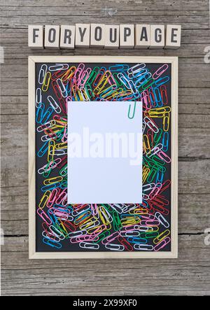 Black background with colorful paper clips, white copy space and wooden cubes with the text: Foryoupage Stock Photo
