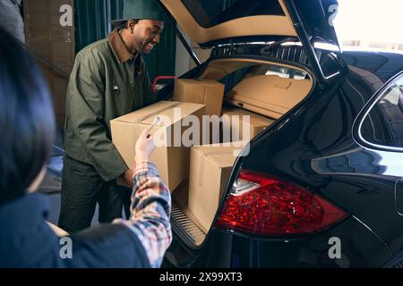 Young man unpacks things from the trunk of a car Stock Photo