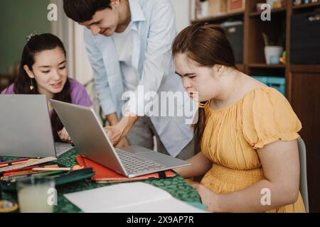 Woman with down syndrome learning through laptop by siblings at home Stock Photo