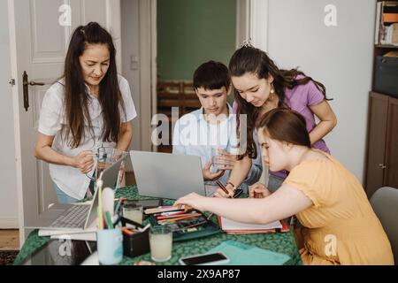 Mother serving water to children studying at home Stock Photo