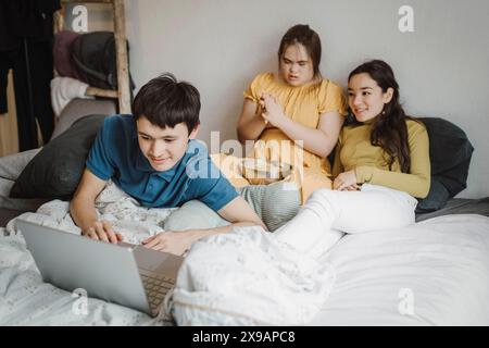Siblings watching movie on laptop with down syndrome sister at home Stock Photo