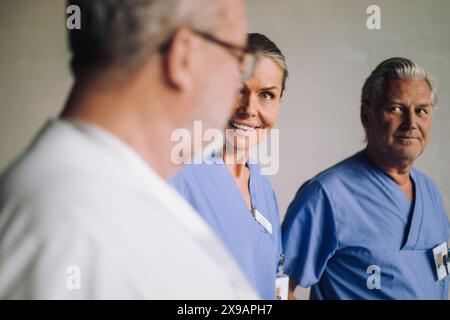 Happy female senior doctor talking with male colleagues in hospital Stock Photo