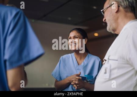 Happy female doctor talking with colleagues in hospital Stock Photo