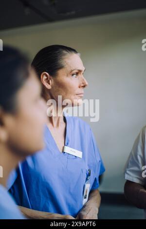 Female doctor in blue scrubs with colleague at hospital Stock Photo