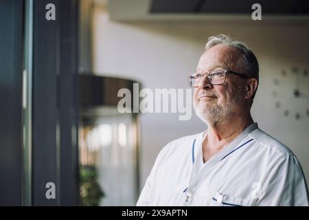 Thoughtful senior male physician in uniform at hospital Stock Photo