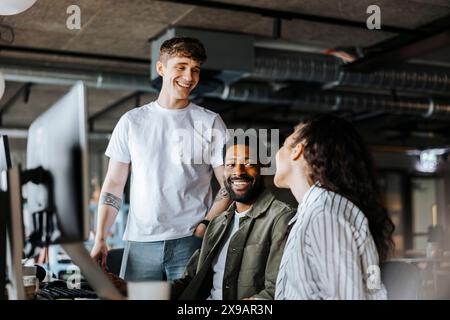 Smiling male entrepreneurs talking with female colleague at office Stock Photo